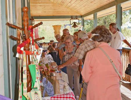 Picnic guests shopping for raffle baskets and silent auction items on Ely Stage Stop porch during the 2013 “Picnic on the Porch.” Photo courtesy of Greg Blinn. 2013elyporchshopping
